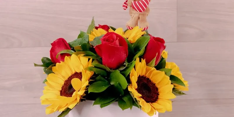 box with sunflowers, roses and a teddy bear