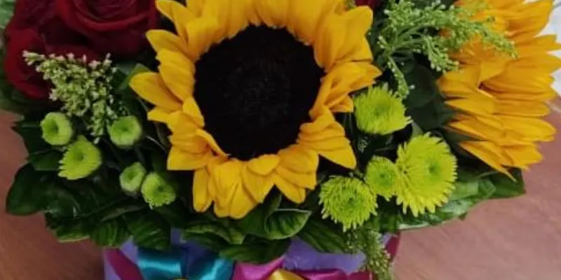 caja de girasoles y rosas más fino follaje 