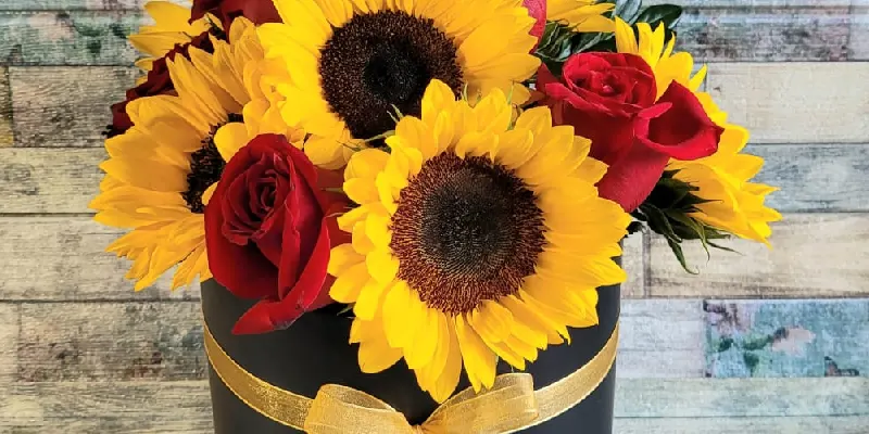 caja de girasoles y rosas con cinta doradas