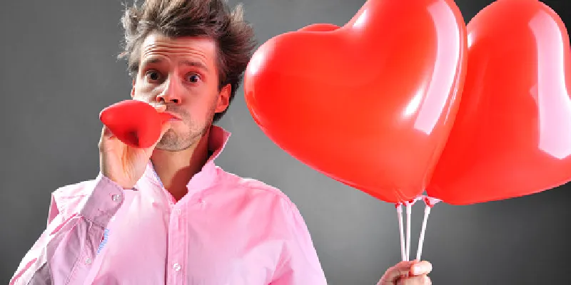 hombre que agarra corazón rojo en forma de globos es inflar