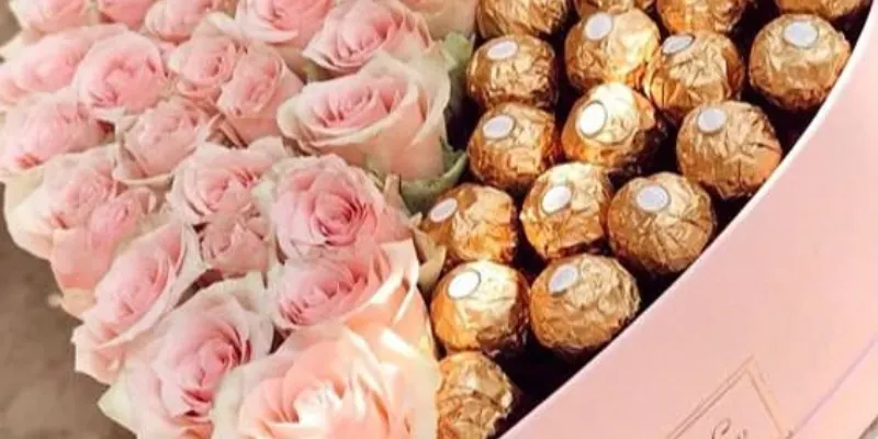 caja mediana con chocolates ferrero y rosas rosadas en la mitad 